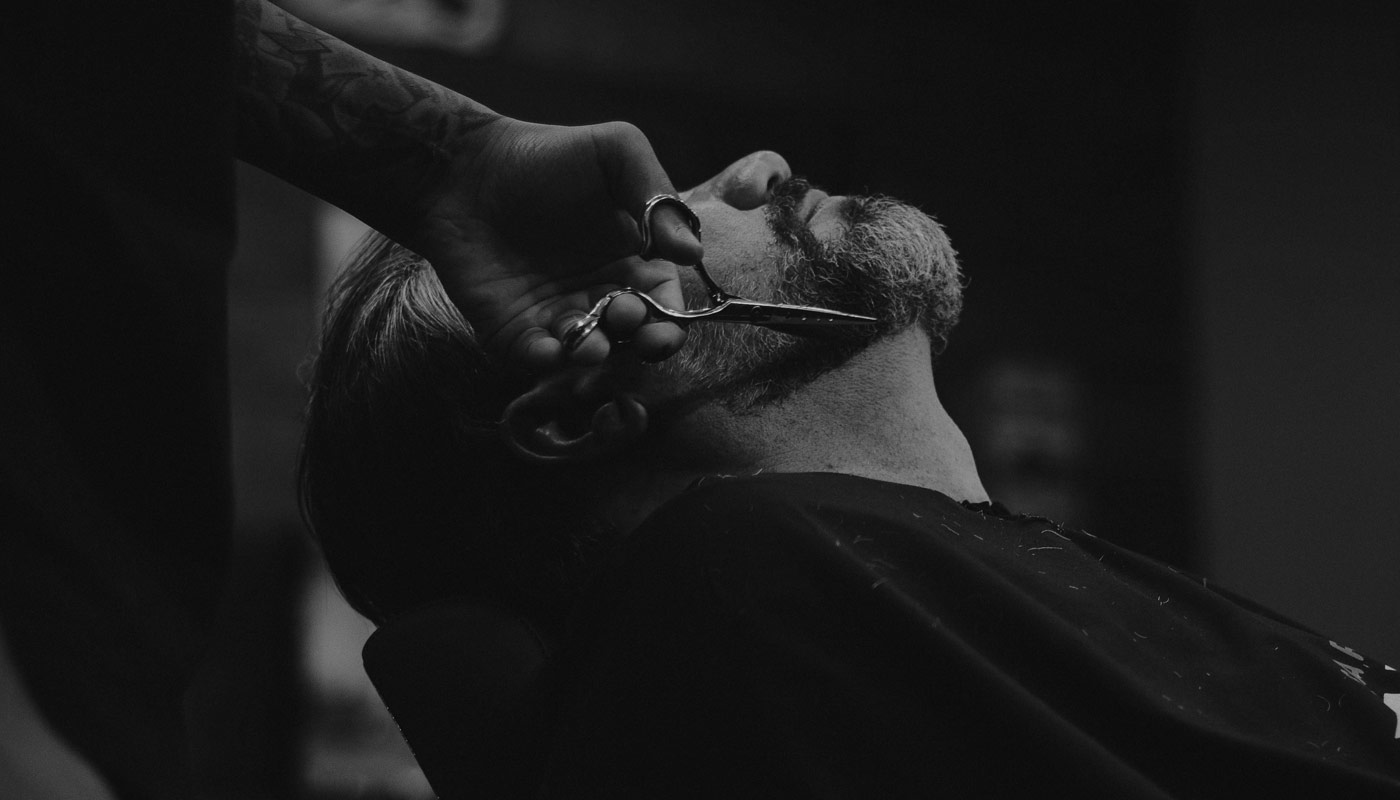 Barber trimming a beard with scissors